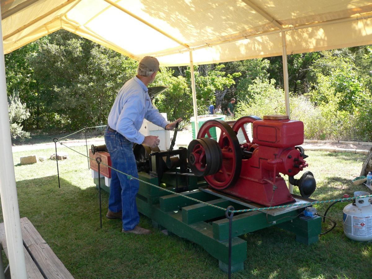 A single-cylinder hit-or-miss engine powers a gristmill for grinding corn